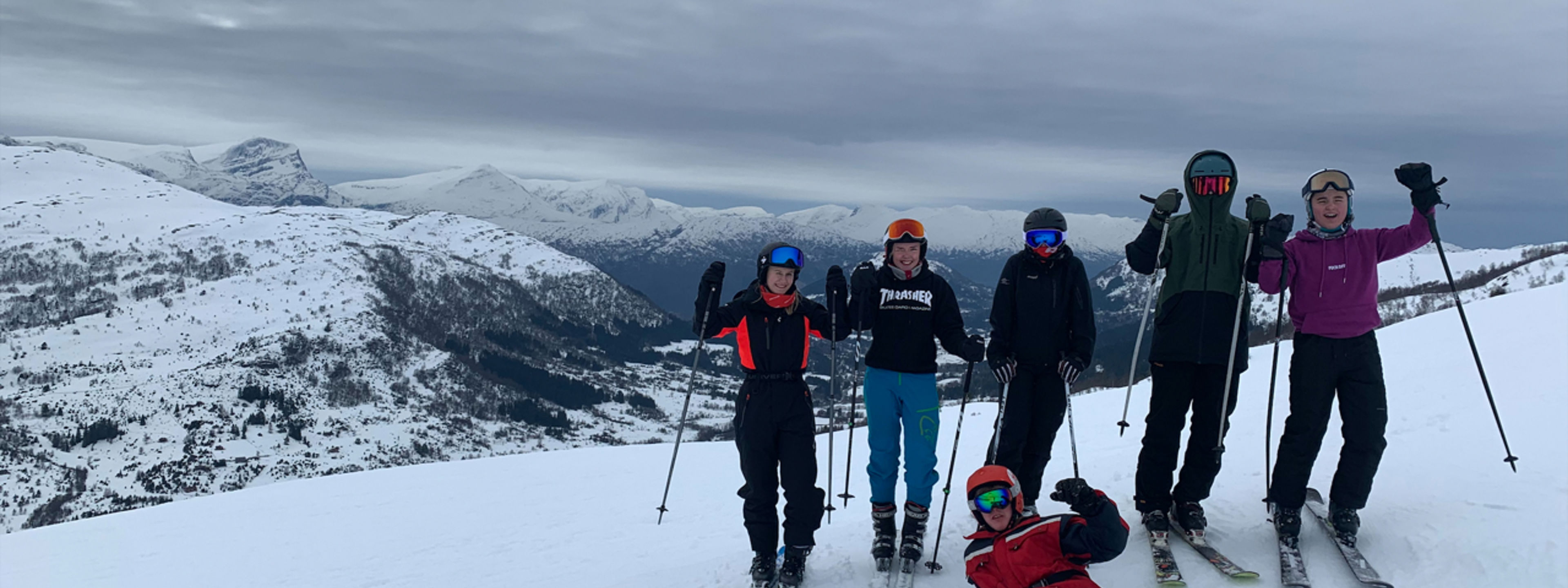 5 elevar på slalom og ein som ligg på bakken med snowboard. 