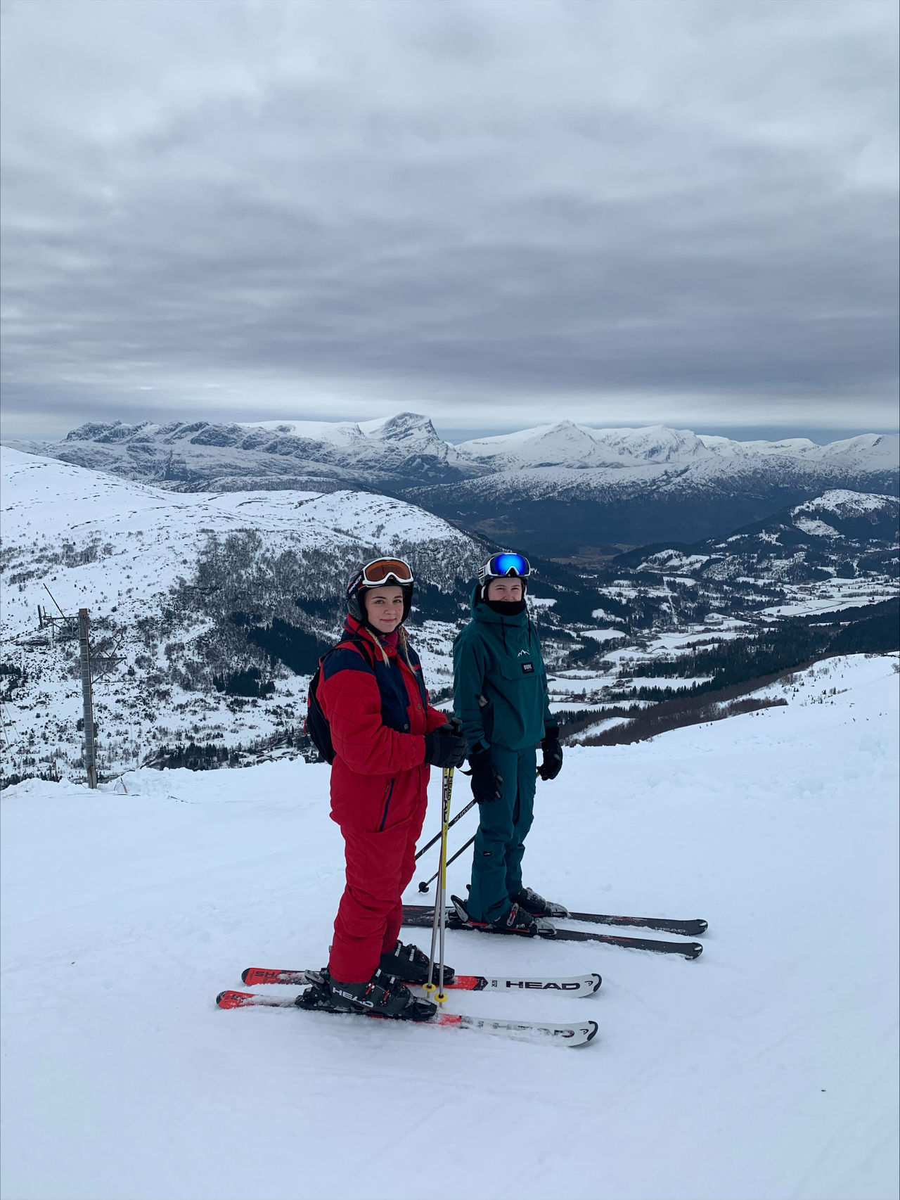 To elevar kledd i skiutstyr står med ski på beina.