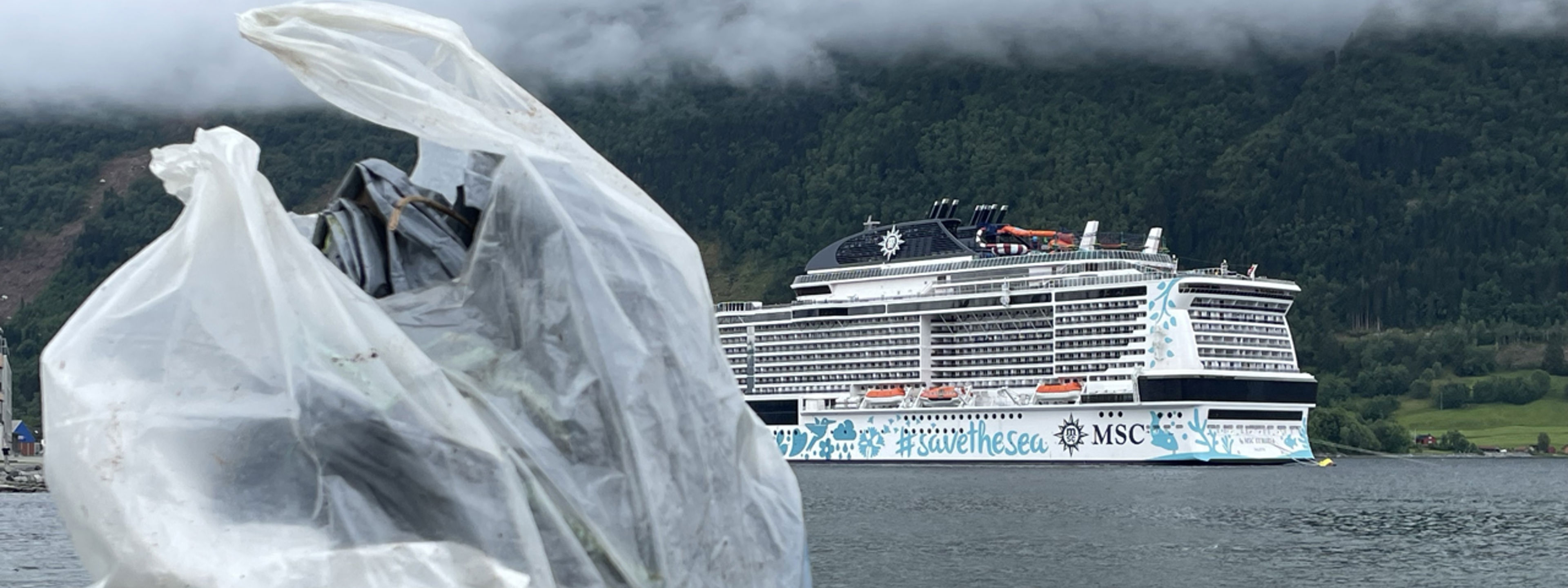 I framgrunnen står det to plastposar med plastsøppel og i bakgrunnen ser du eit cruise skip.