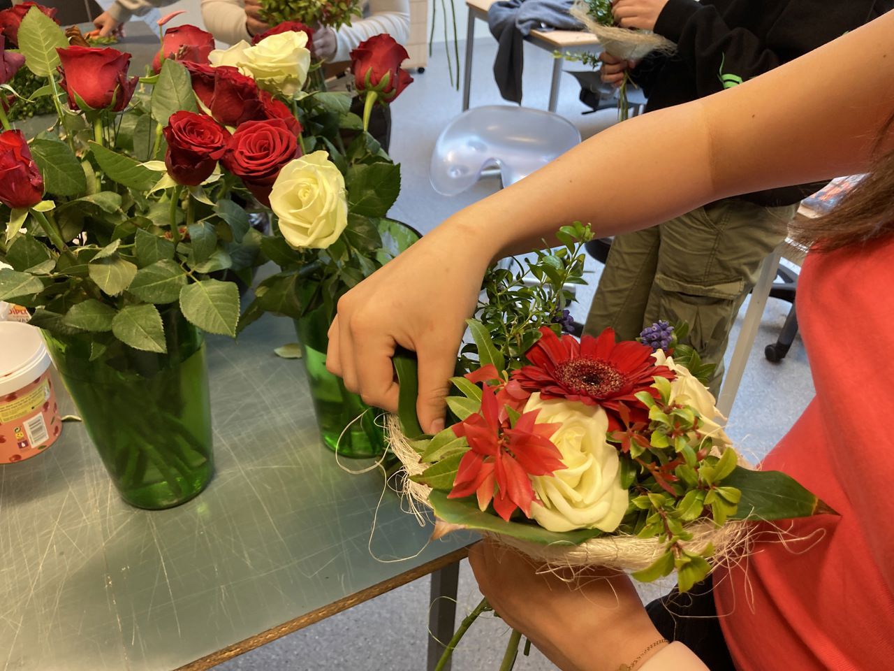 Elev arbeidar med blomsterdekorasjon. Her set eleven inn vintergrønt i lag med nellik og roser.