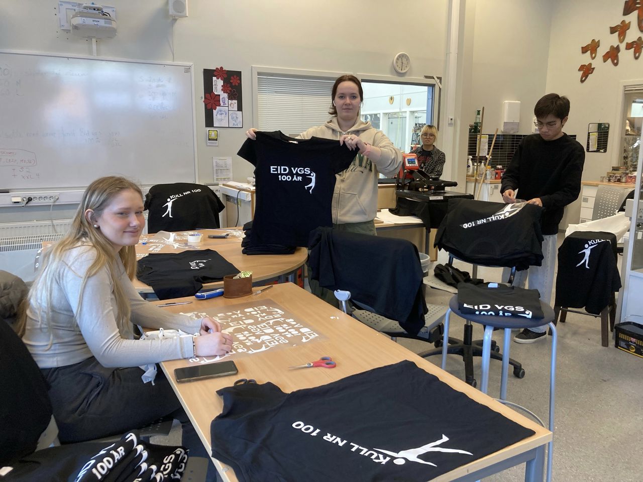 Elevar konsentrera seg om arbeid med t-skjorter. Fire elevar i bilete jobbar med ulike prosessar.